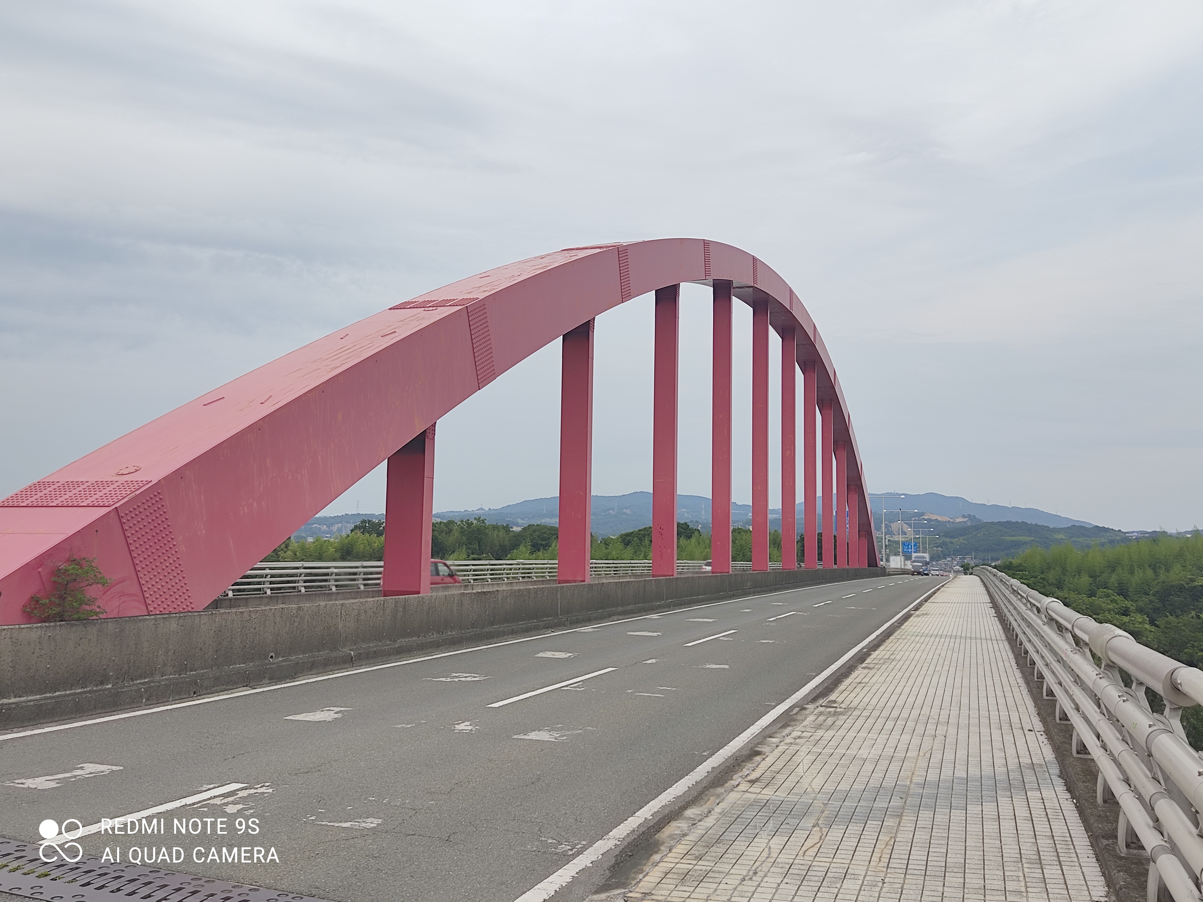 a bridge with a large red arch over a road